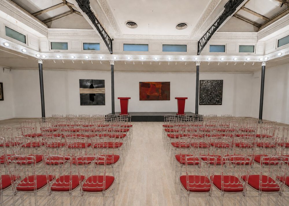 Studio Liberty — platea con sedie trasparenti e podi per relatori